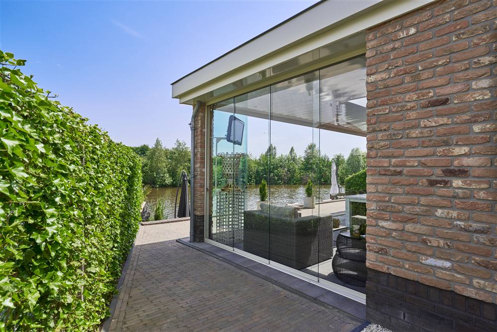 Glass veranda with brick pillars overlooking a garden and water